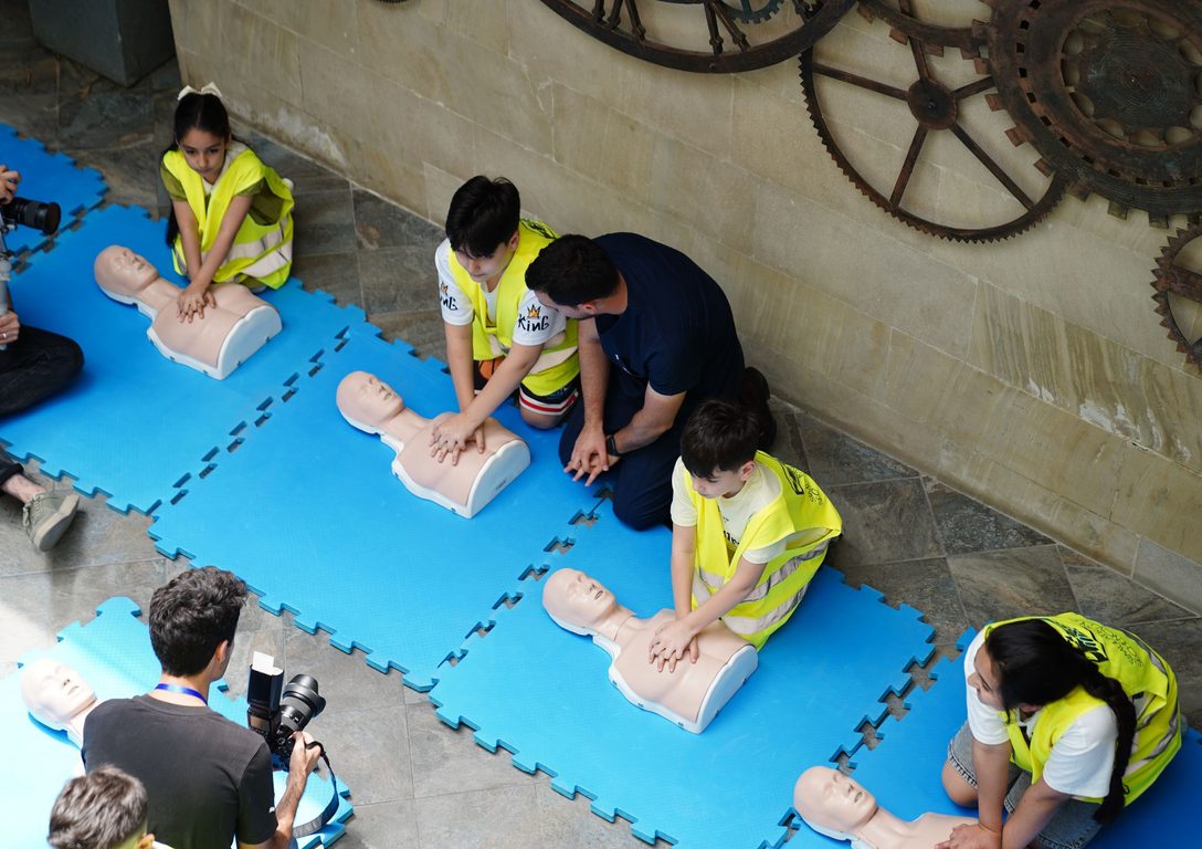 Workplace first-aid class in hi-vis safety vests practising CPR on manikins with an instructor